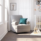 Gray armchair with a teal pillow in a bright room with white walls and wooden floor.