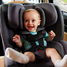 Child in a car seat with a happy expression, sitting in a vehicle.