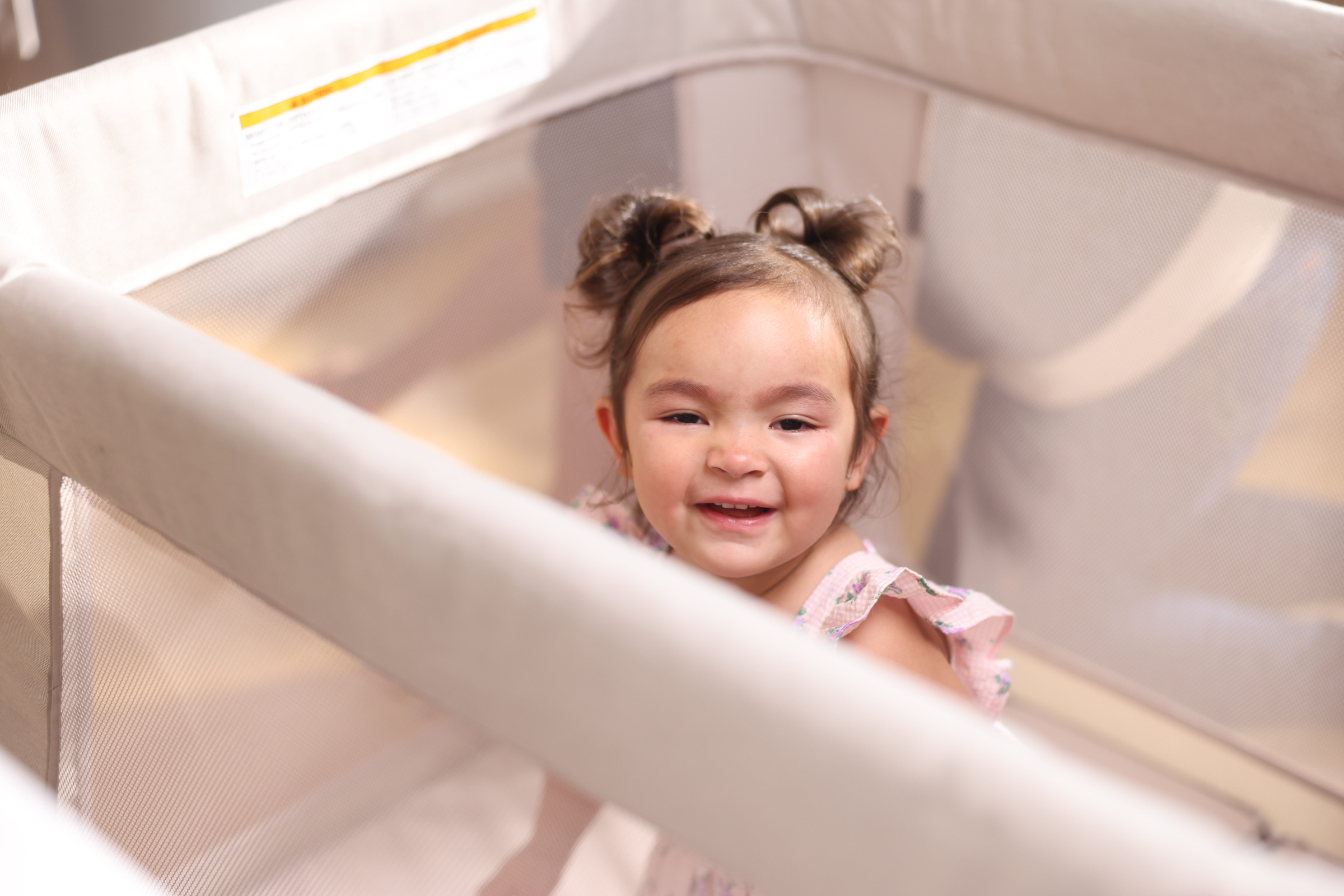 toddler sitting up in playpen