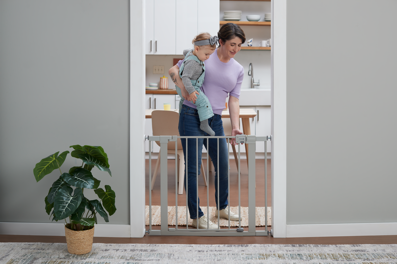 mother adjusting gate with toddler in her arms