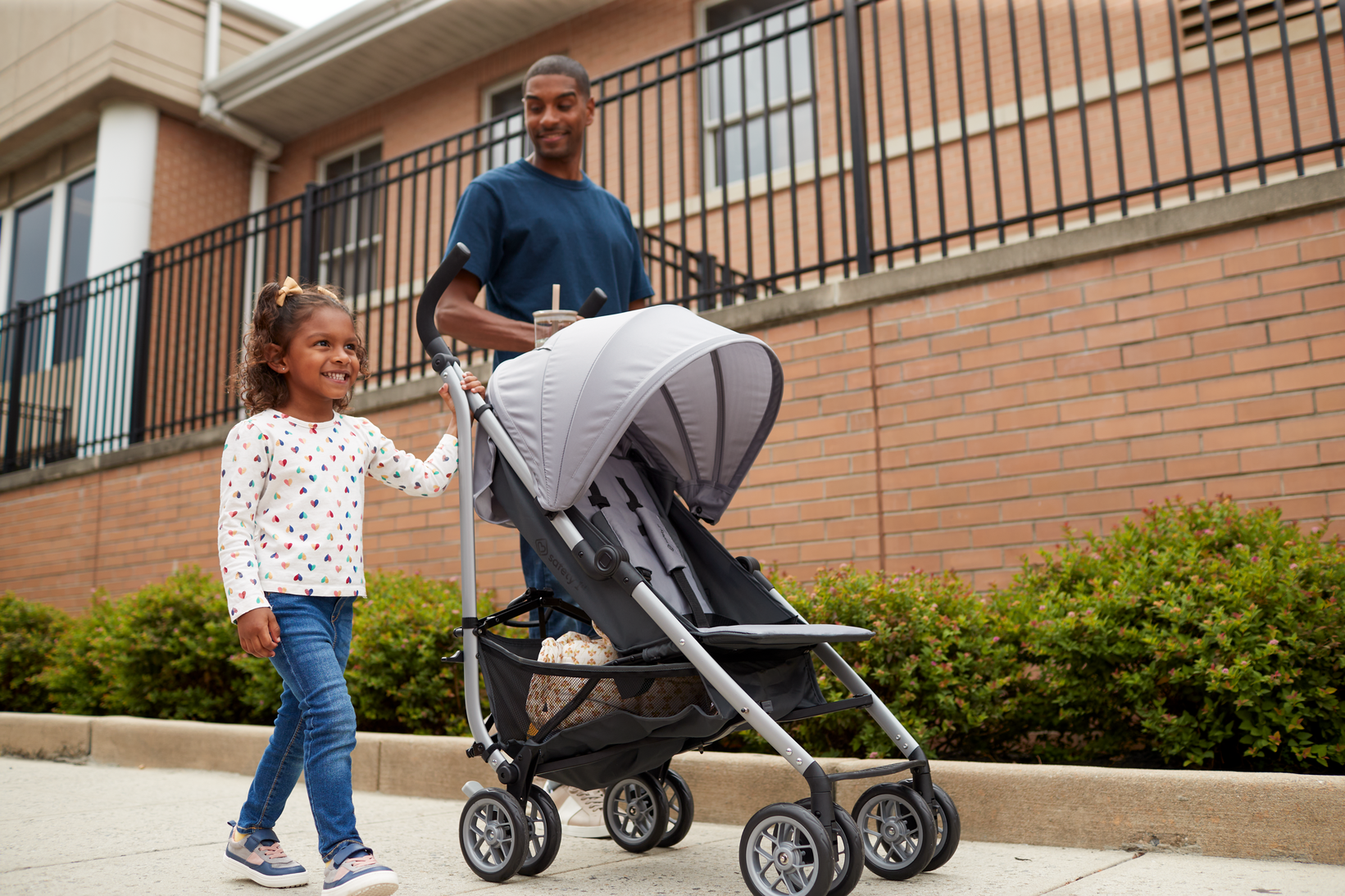 Father and daughter walking beside stroller