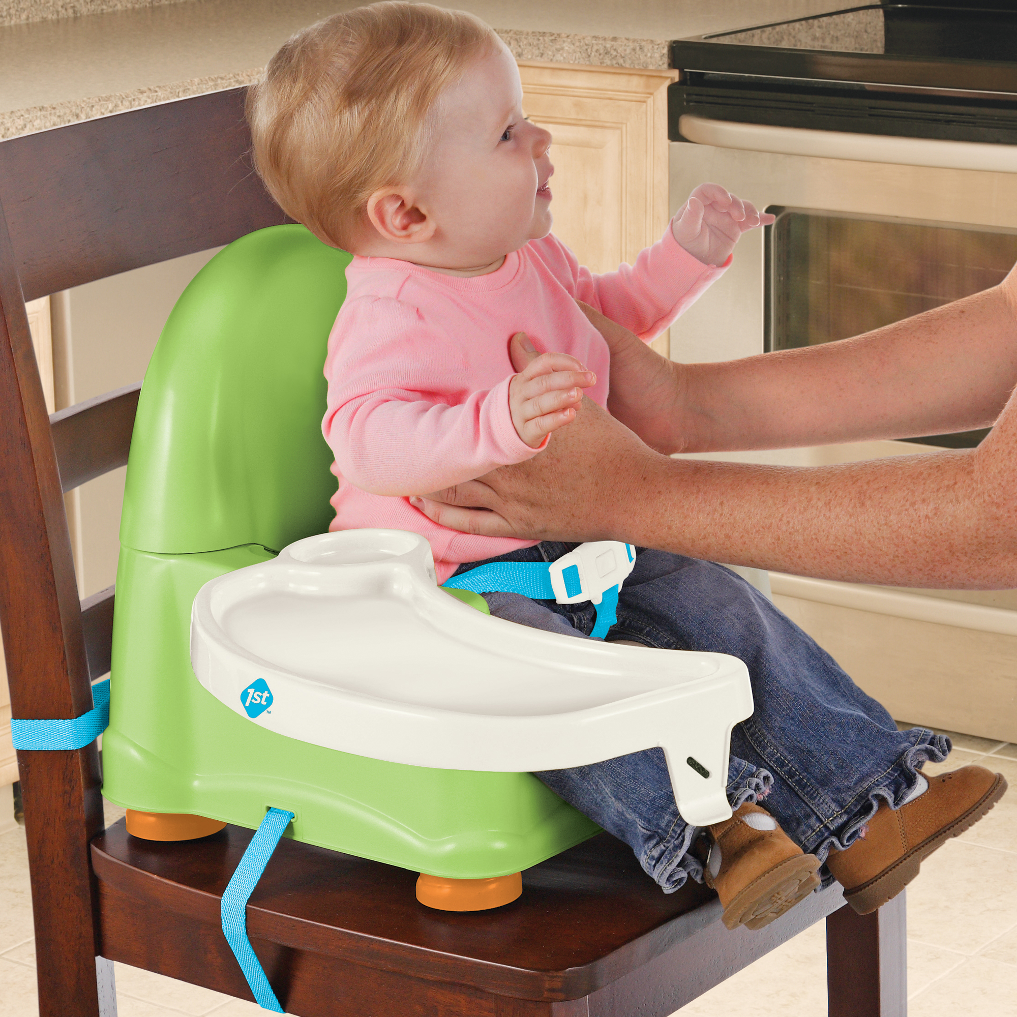 child getting set in green booster seat