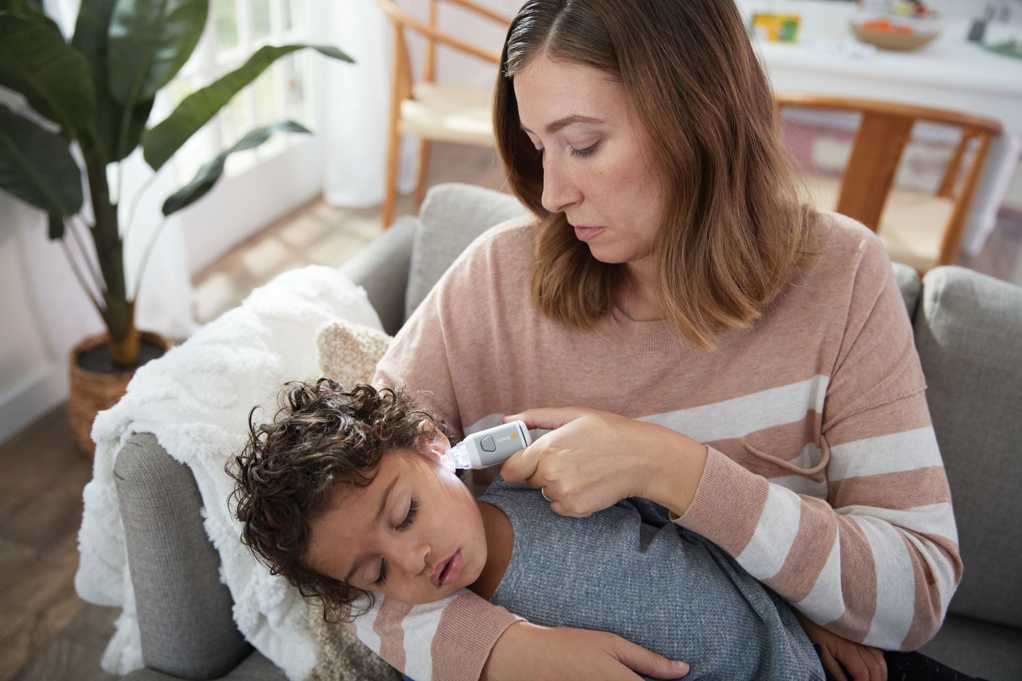 Mom using outer ear cleaner attachment on son