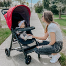 baby in red stroller outside with mom