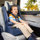 Child in a car seat inside a vehicle with trees outside