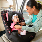 Woman adjusting a child in a car seat with Minnie Mouse design.