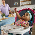Baby in a high chair with bubbles floating around, kitchen in the background