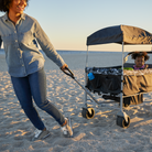 Woman pushing Summit Sprint Quad Wagon Stroller with a child on a sandy beach