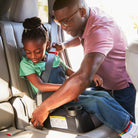 Man adjusting a child's car seat in a vehicle