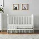 White crib with bedding in a room with framed animal pictures on the wall.